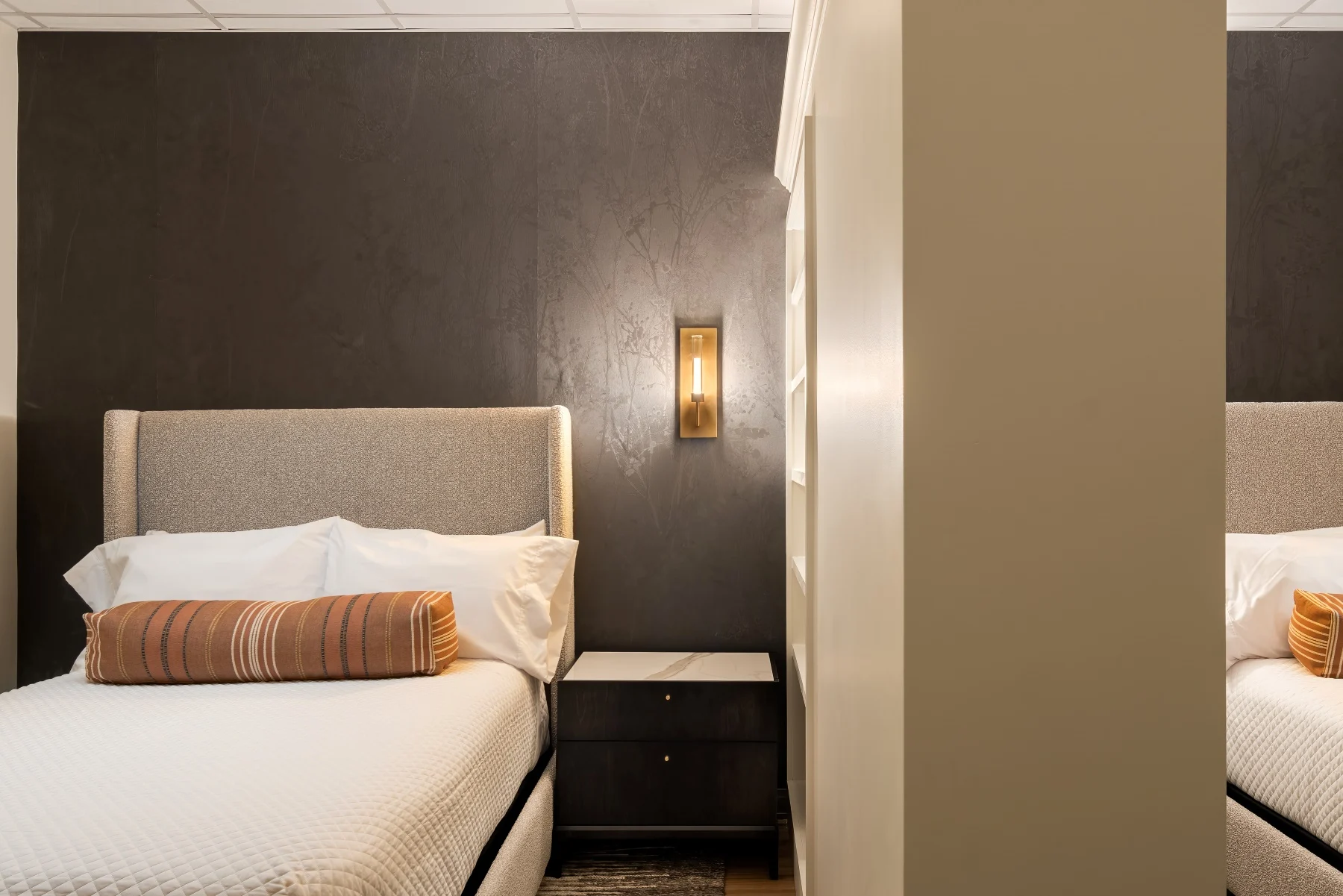 Luxury double room with a textured dark wall, plush bedding, and bedside table, emphasizing comfort and privacy for detox clients at APN DFW.