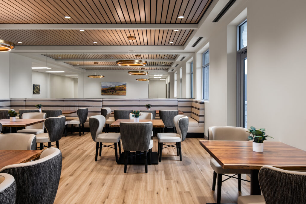 Modern dining area at All Points North DFW featuring wooden tables, comfortable seating, and natural light, designed for a supportive environment in addiction recovery.